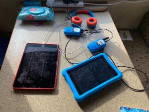 Mobile devices, iPad, Kindle Fire, Walkie Talkie and Headphones charging on a table